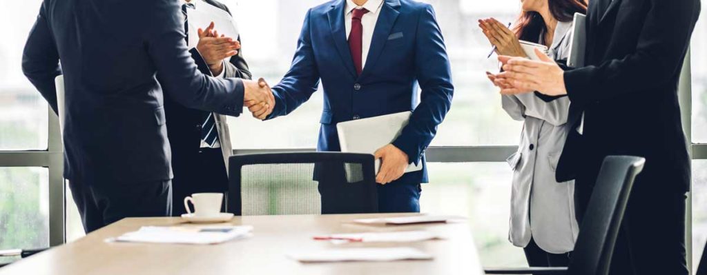 Image two business partners in elegant suit successful handshake together in front of group of casual business clapping hands in modern office.Partnership approval and thanks gesture concept